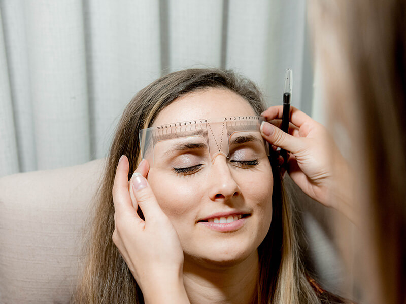An artist mapping a client's brows before shaping